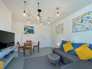 Una sala moderna con sofá, reposapiés, mesa de comedor, sillas y obras de arte en las paredes.