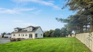 A house with a sloped roof, a garage, and a well-maintained lawn. - 4 bedroom accommodation in Southerness (Southerness)