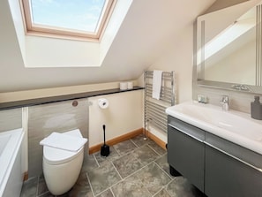 Ein modernes Badezimmer mit Oberlicht, Toilette, Bidet, Waschbecken und Spiegel.