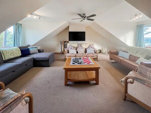 Een loft-woonkamer met plafondventilator, een salontafel met een gezelschapsspel, en een zithoek.