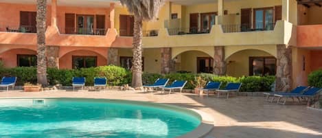 A resort with a pool, lounge chairs, and a two-story building with balconies.