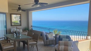 A balcony with a view of the ocean, furnished with chairs and a table.