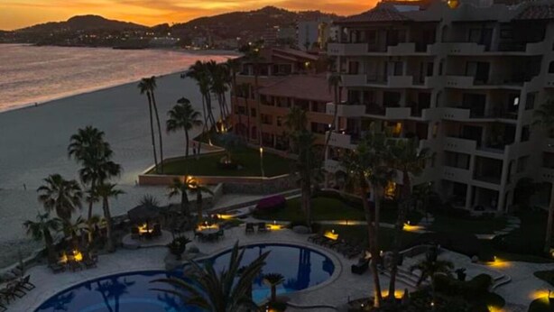 A resort with multiple swimming pools, palm trees, and a beach view.