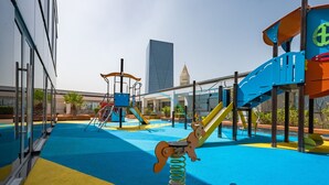 A playground with a slide, climbing structures, and a spring-mounted horse ride. - Lively Studio in Sky Gardens, DIFC by Deluxe Holiday Homes (Dubai)