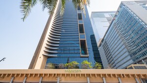 A tall building with a modern glass facade and a sign reading "SkyGardens Hotel". - Lively Studio in Sky Gardens, DIFC by Deluxe Holiday Homes (Dubai)