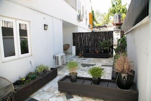 A courtyard with potted plants, a chair, and a small table. - Orange Roof Lodge (Abuja)