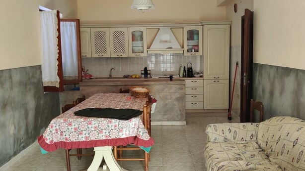 A compact kitchen with a dining table and a patterned sofa. - Staropoli house is located 3;5km from the sea in Briatico, 15km from tropea, (Sciconi di Briatico)