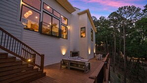 A wooden deck with a bench and a fireplace, surrounded by trees. - Heavenly Falls Cabin in Broken Bow | Waterfall Retreat (Broken Bow)