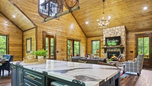 Una cocina amplia con una isla grande, paredes de madera y una chimenea de piedra.