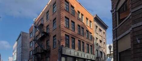A multi-story building with a brick facade, large windows, and a fire escape.