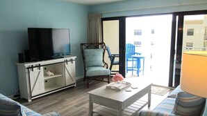 Un salon comprenant un téléviseur, un canapé, un fauteuil et une table basse.