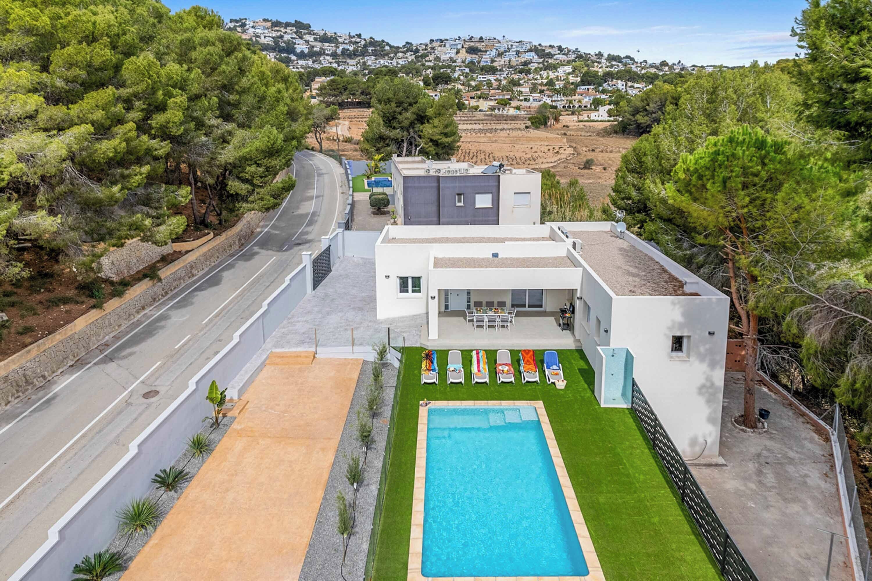 Une maison moderne avec une piscine, une route et une vue sur une ville en arrière-plan.