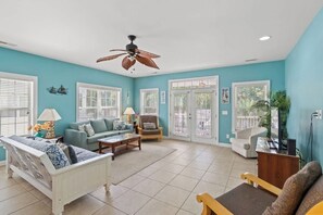 A spacious living room with a ceiling fan, a sofa, a chair, and a coffee table.