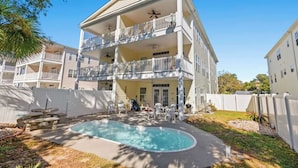 A multi-story building with a pool, outdoor seating, and a covered patio.