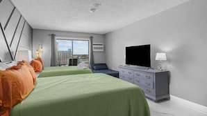 Une chambre d’hôtel avec deux lits, une télévision, une commode et une fenêtre donnant sur la ville.