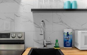 A kitchen with a stainless steel oven, a modern faucet, and a microwave.