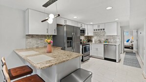 Eine moderne Küche mit Granit-Arbeitsplatten, Edelstahlgeräten und einer zentralen Kochinsel mit Sitzgelegenheiten.