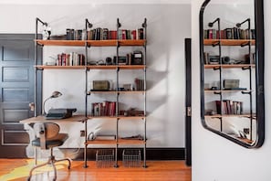 A room with a desk, a vintage typewriter, a bookshelf, and a mirror.