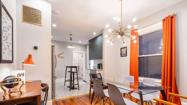 A modern kitchen with a large window, a dining area with a glass table, and a bright chandelier. - Mid-Century Marvel Steps from Restaurants and Bars (Washington)