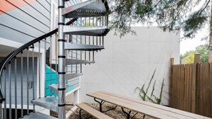 A spiral staircase with metal railings, a wooden bench, and a picnic table in a backyard setting. - Mid-Century Marvel Steps from Restaurants and Bars (Washington)