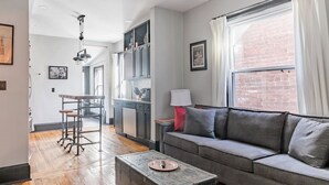 Un salon moderne avec un canapé gris, une table basse et un coin repas comprenant une table et des chaises.
