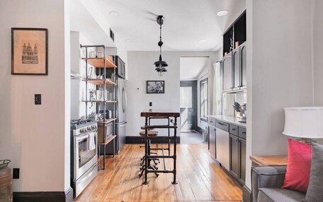 A modern kitchen with wooden flooring, stainless steel appliances, and a central island.