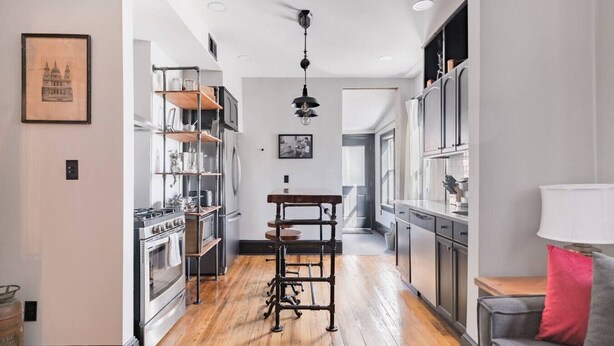 Une cuisine moderne avec un plancher en bois, des appareils électroménagers en acier inoxydable et un îlot central.
