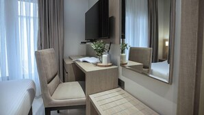 Una habitación de hotel con cama, escritorio, silla, televisión y espejo.