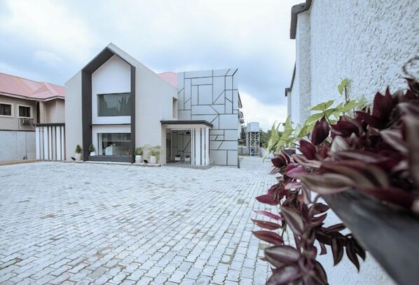 En modern byggnad med en geometrisk fasad, en stenlagd innergård och krukväxter.
