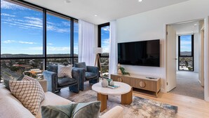 Un salon moderne doté d’un grand téléviseur, de sièges confortables et offrant une vue sur la ville.