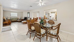 A spacious living room with a dining area, a ceiling fan, and a large mirror reflecting the kitchen. - Spacious 4-bedroom house with 2 master suites in lovely Port Charlotte. (Port Charlotte)