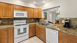 A kitchen with wooden cabinets, a microwave, stove, sink, and dishwasher. - Spacious 4-bedroom house with 2 master suites in lovely Port Charlotte. (Port Charlotte)