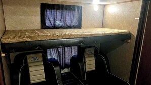 A bunk bed with a headboard, two seats with headrests, and a small table. - Ample Lakeside Travel Trailer (Bridgeport)