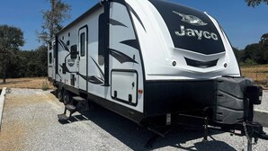 A Jayco RV parked on gravel with a clear sky in the background. - Ample Lakeside Travel Trailer (Bridgeport)