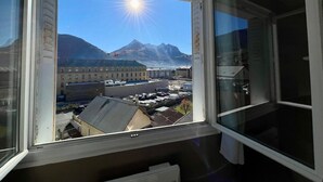 A window with a view of a mountain and buildings. - Charming T3 with balcony in the heart of Briançon (Briançon)