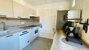 A modern kitchen with white cabinets, a built-in oven, a microwave, and a coffee maker. - Charming T3 with balcony in the heart of Briançon (Briançon)