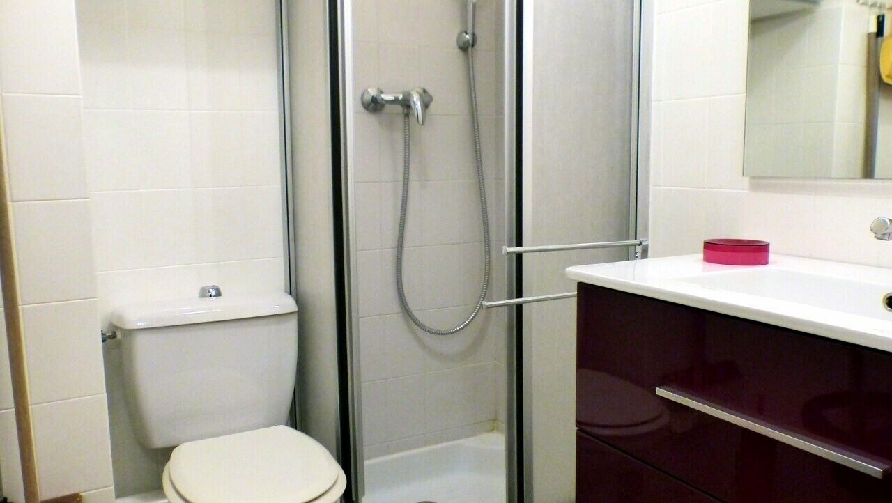 Un baño con inodoro, cabina de ducha y tocador con espejo.