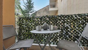 An outdoor seating area with a round table and two chairs, a patterned wall, and a building in the background.