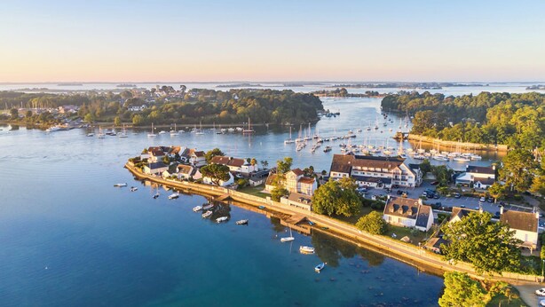 A coastal town with a marina filled with boats, surrounded by residential buildings and greenery. - Charming T3 with balcony near beach (Vannes)