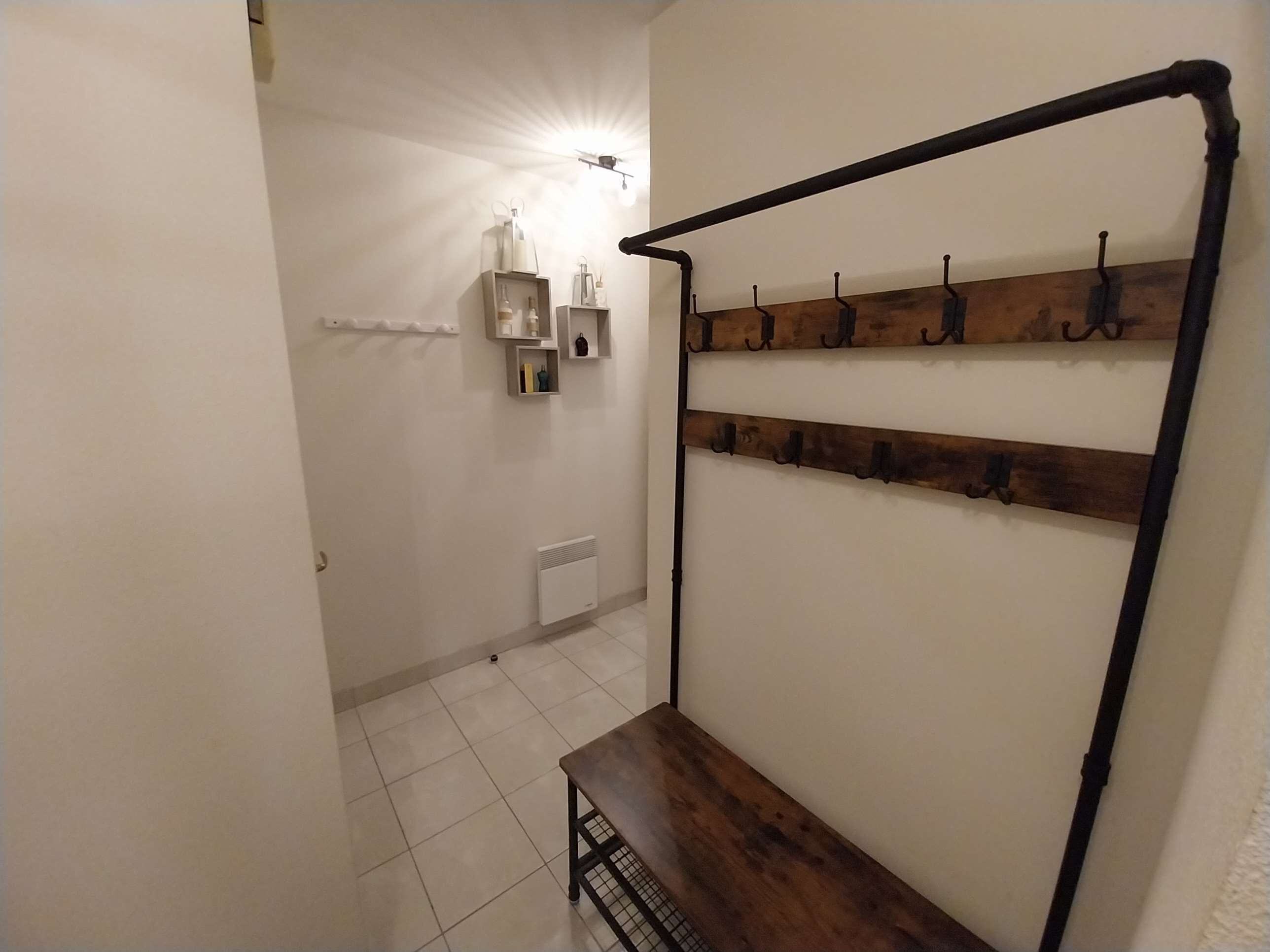 A hallway with a coat rack, a radiator, and a shelf with toiletries.