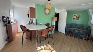 A modern kitchen with a dining area, a sofa, and a small table. - Bourgeois apartment (Trouville-sur-Mer)