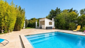 A swimming pool with a small building, likely a sauna or hot tub, in the background.