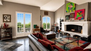 A spacious living room with a fireplace, a sofa, a coffee table, and a large window.