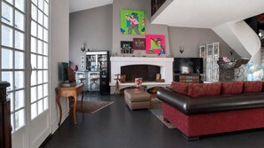 A spacious living room with a fireplace, a television, and a red sofa.