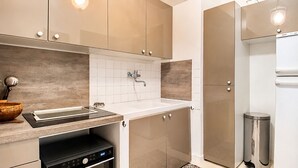 A modern kitchen with a built-in oven, a sink, and a stainless steel trash can.