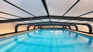 An indoor swimming pool with a clear blue water surface, surrounded by a curved ceiling structure.