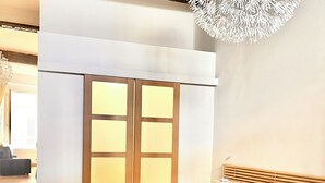Een moderne slaapkamer met een bed, nachtkastje, lamp en een decoratieve plafondlamp.