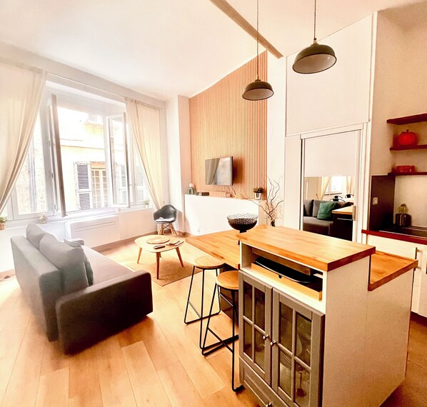 Una sala moderna con un sofá, una mesa de comedor y una zona de cocina con barra.
