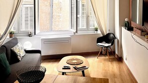 Een moderne woonkamer met een bank, een salontafel, een stoel, een radiator en een raam met gordijnen.