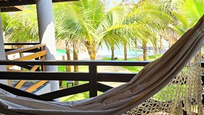 Una hamaca bajo una pérgola de madera con vista a palmeras y un piso de baldosas.